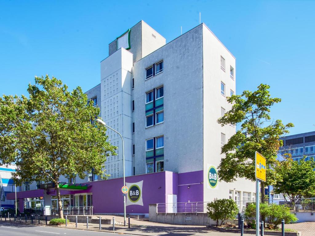 un edificio blanco alto en una calle de la ciudad en B&B Hotel Offenbach-Kaiserlei, en Offenbach