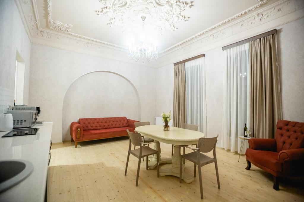 sala de estar con mesa y sofá rojo en Moedani-Very Center Apartments in Kutaisi, en Kutaisi