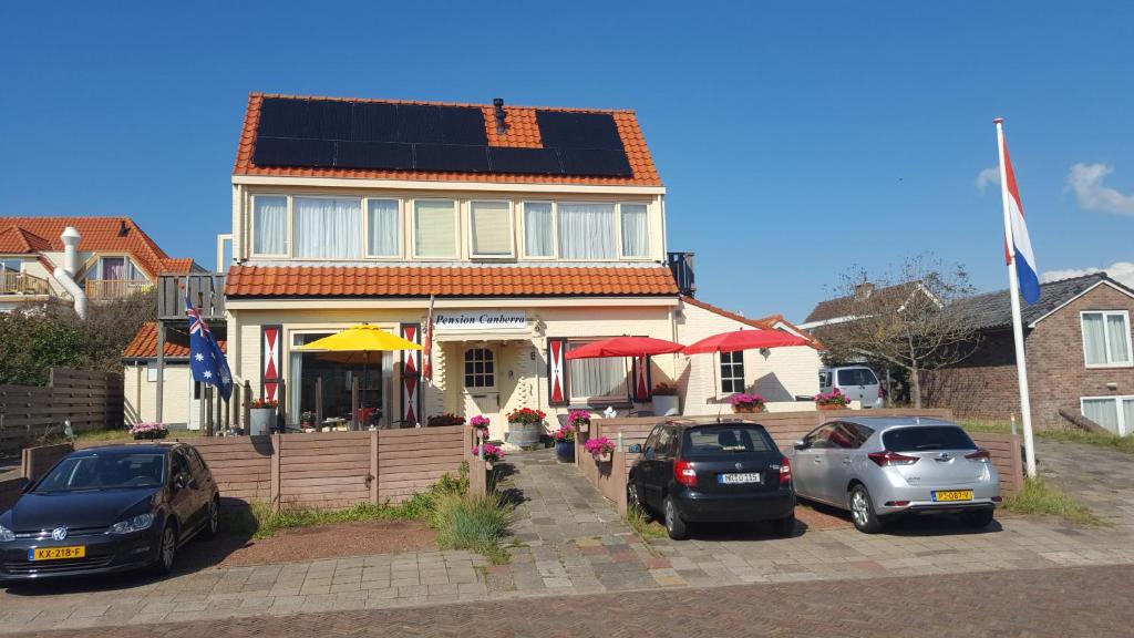 una casa con coches aparcados delante de ella en Appartement Canberra., en Bergen aan Zee