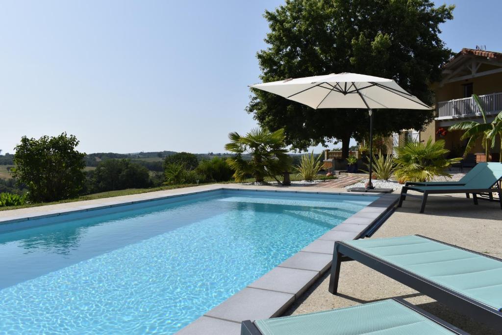 una piscina con sombrilla, mesa y sillas en Maison A Vallon, en Couloumé-Mondébat