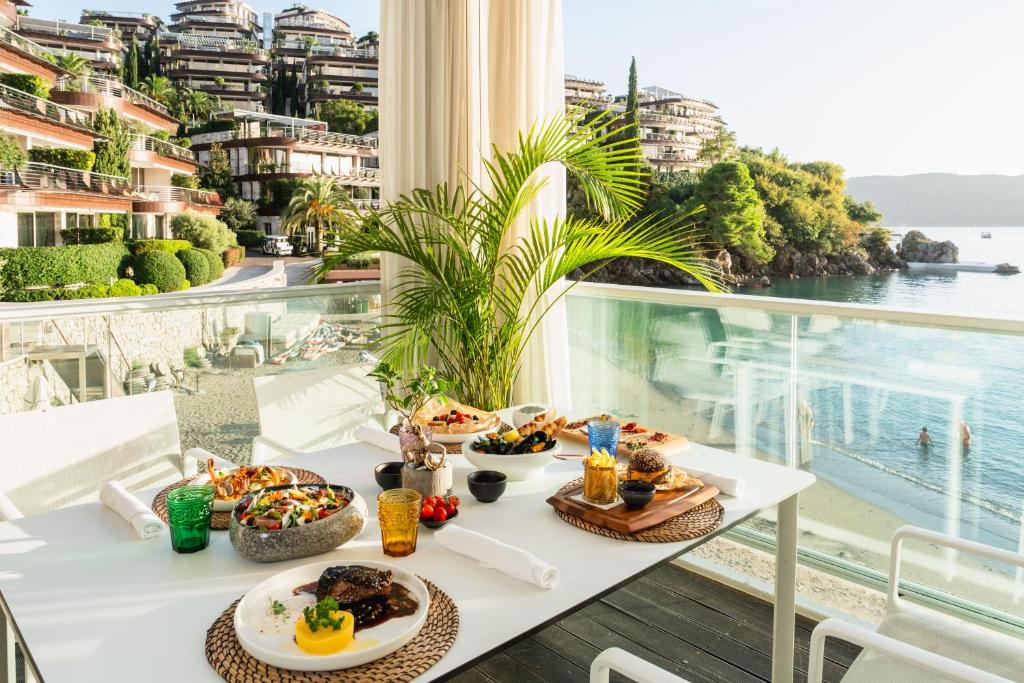 a table with food on a balcony with a view of the water at Dukley Hotel & Resort in Budva