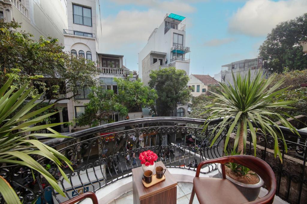 un balcón con sillas y una mesa con flores en La Lisa Hotel, en Hanói