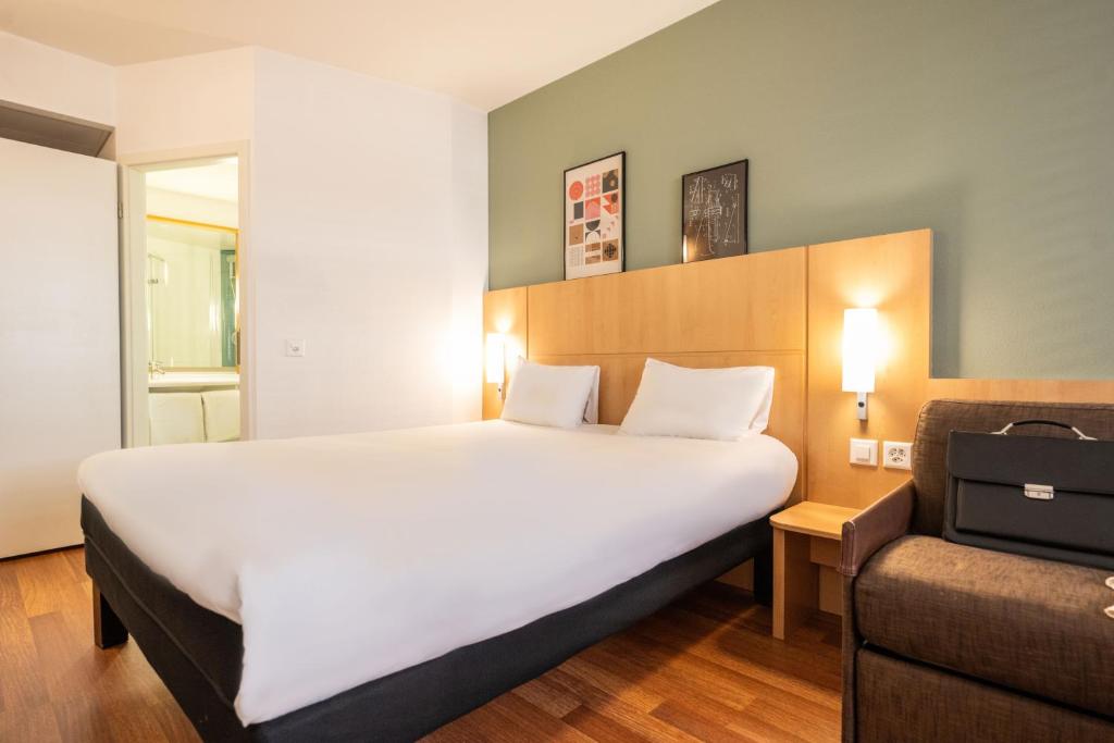 una habitación de hotel con una cama grande y una silla en ibis Genève Centre Nations, en Ginebra