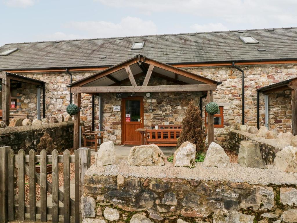 uma antiga casa de pedra com uma porta de madeira e uma cerca em Barn 2 em Swansea