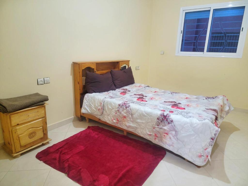 1 dormitorio con 1 cama grande con alfombra roja en Appartement de luxe Nour, en Fez