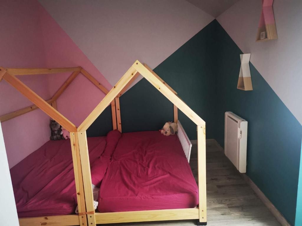 um quarto para crianças com um beliche de madeira com lençóis roxos em Le Mans Fay sa course em Fay