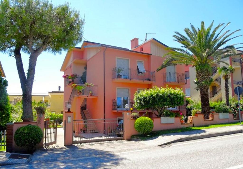 una casa rosa con palme di fronte a una strada di PATRIZIA - Vicino al centro, con 3 camere e posto auto a Numana