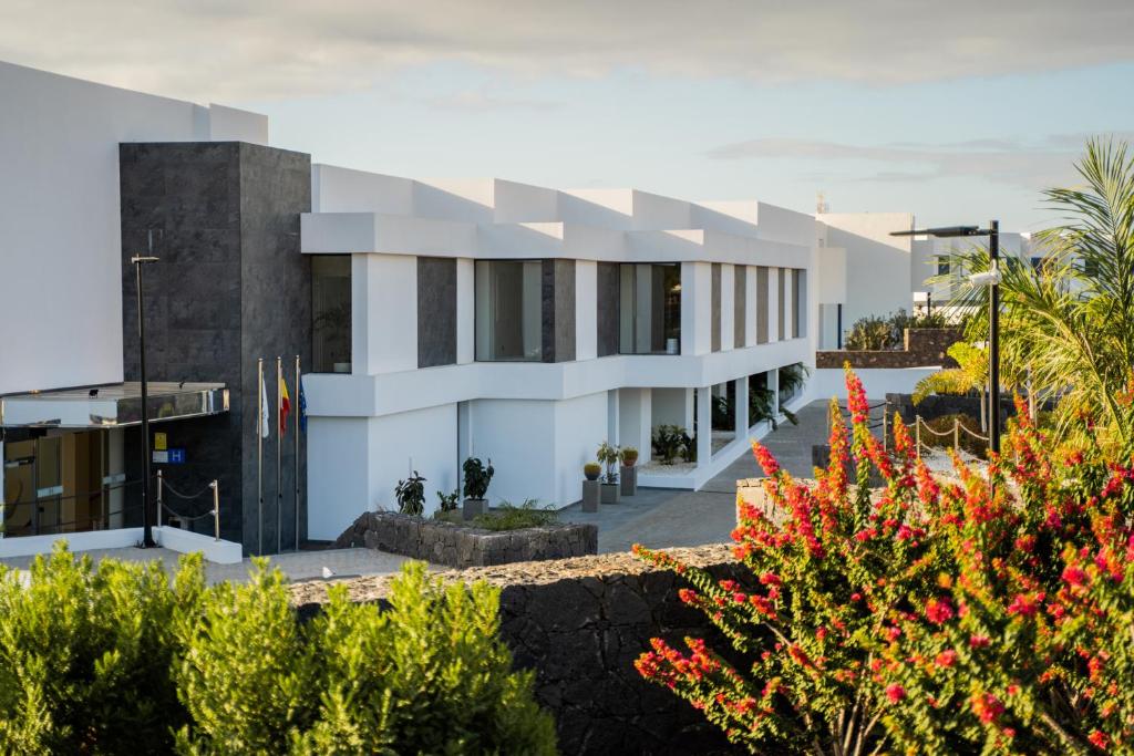 a white building with red flowers in front of it at Royal Marina Suites Boutique Hotel - Adults Only in Puerto Calero