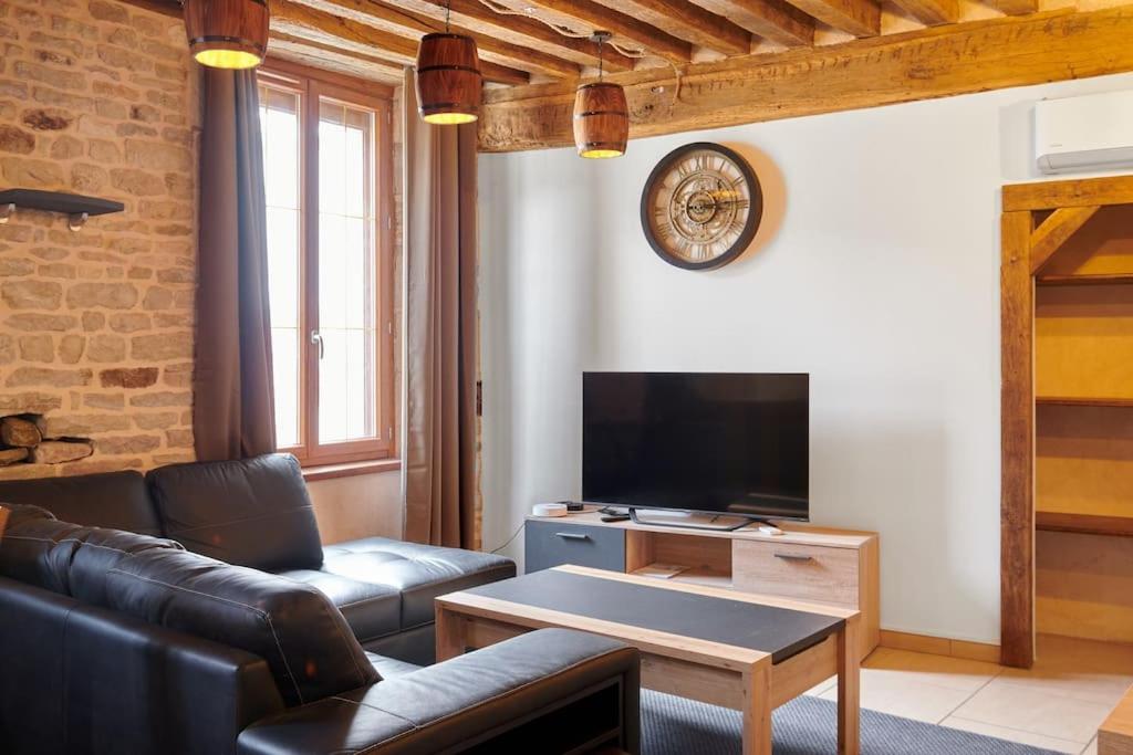 a living room with a couch and a tv at Le Richebourg in Gevrey-Chambertin