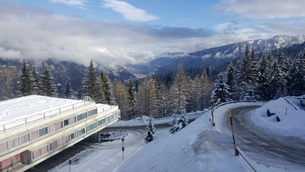 a building on a snow covered slope with a mountain at ABITARE MARILLEVA in Trento