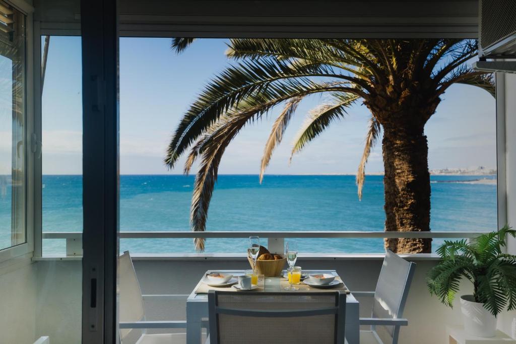 a table and chairs with a palm tree and the ocean at Sobre el mar con vistas a las Dunas de Maspalomas in San Agustin