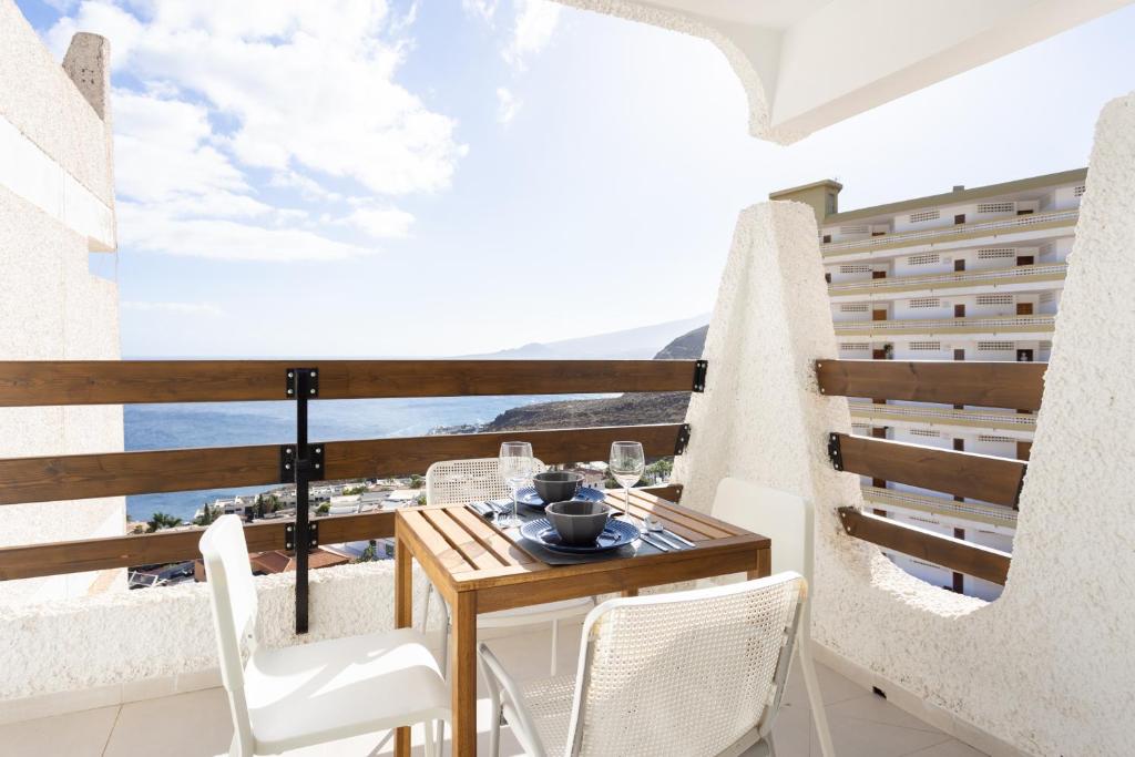 a balcony with a wooden table and white chairs at Home2Book Stylish Studio Ocean View Tabaiba in Tabaiba