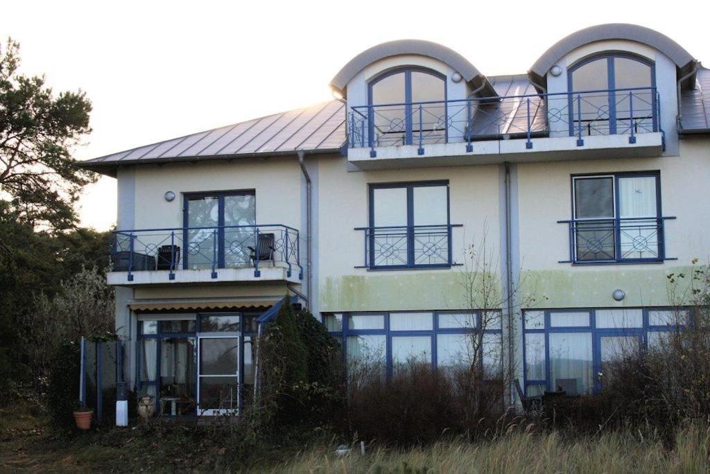 a large white house with windows and a balcony at Ferienwohnung Wellenblick in Trassenheide