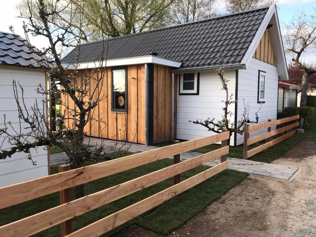 a house with a wooden fence in front of it at Vakantiehuis voor 4 personen in Opheusden