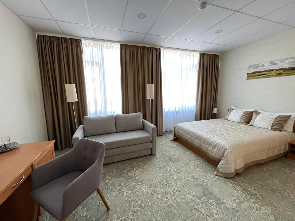 une chambre d'hôtel avec un lit et une chaise dans l'établissement Hotel - cafe Naujoji Akmenė, à Naujoji Akmenė