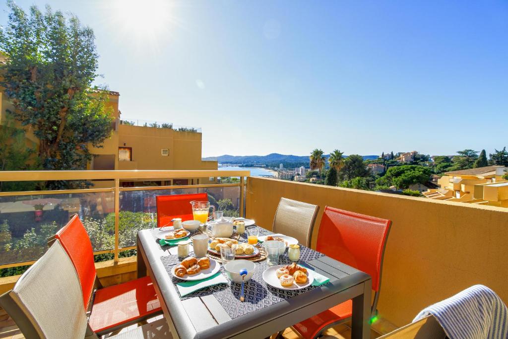 una mesa con platos de comida en el balcón en SELECT' - Appartement avec vue mer, à quelques metres du centre-ville avec parking - DOLCE VITA, en Le Lavandou