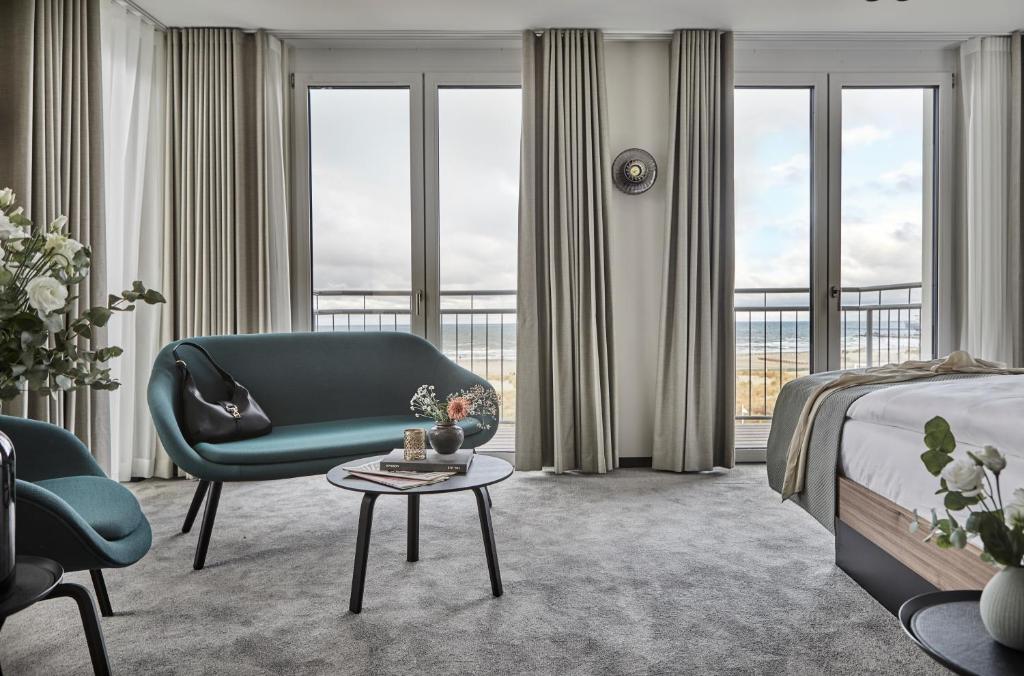 a bedroom with a green chair and a bed and a table at Baltic Hideaways Beach Hotel Warnemünde in Warnemünde