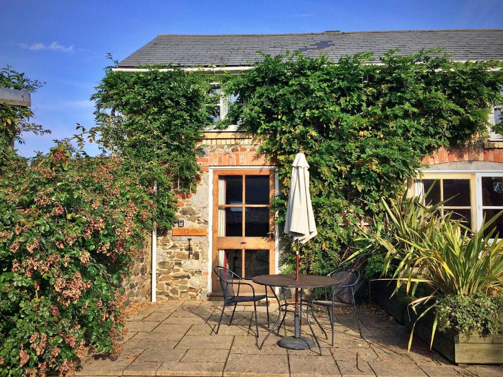 a table and an umbrella in front of a building at Finest Retreats - Little Dunley - Fig Cottage in Bovey Tracey
