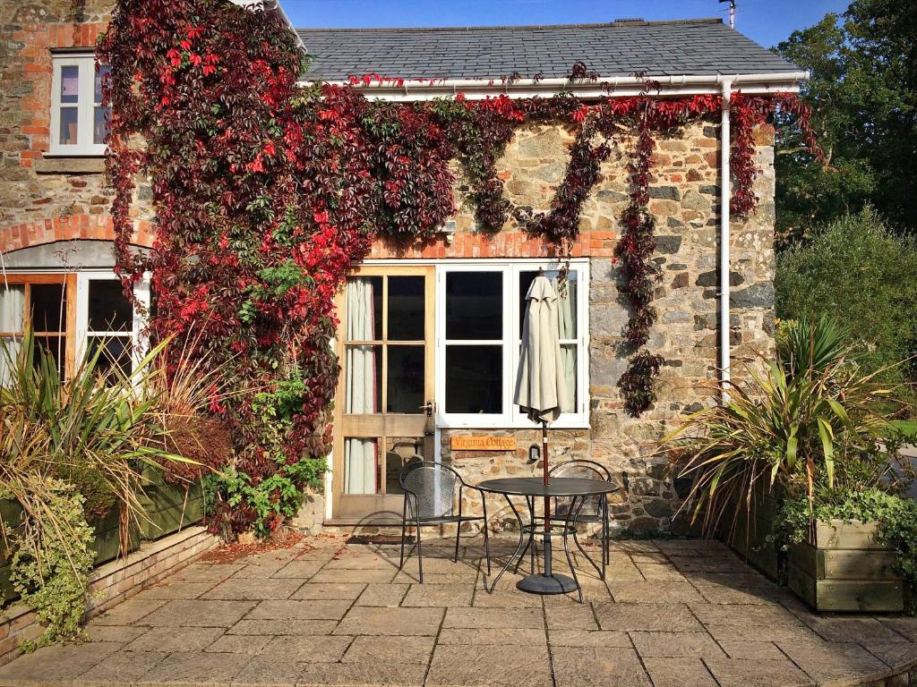 une maison avec une table en face d'une fenêtre fleurie dans l'établissement Finest Retreats - Little Dunley - Virginia Cottage, à Bovey Tracey