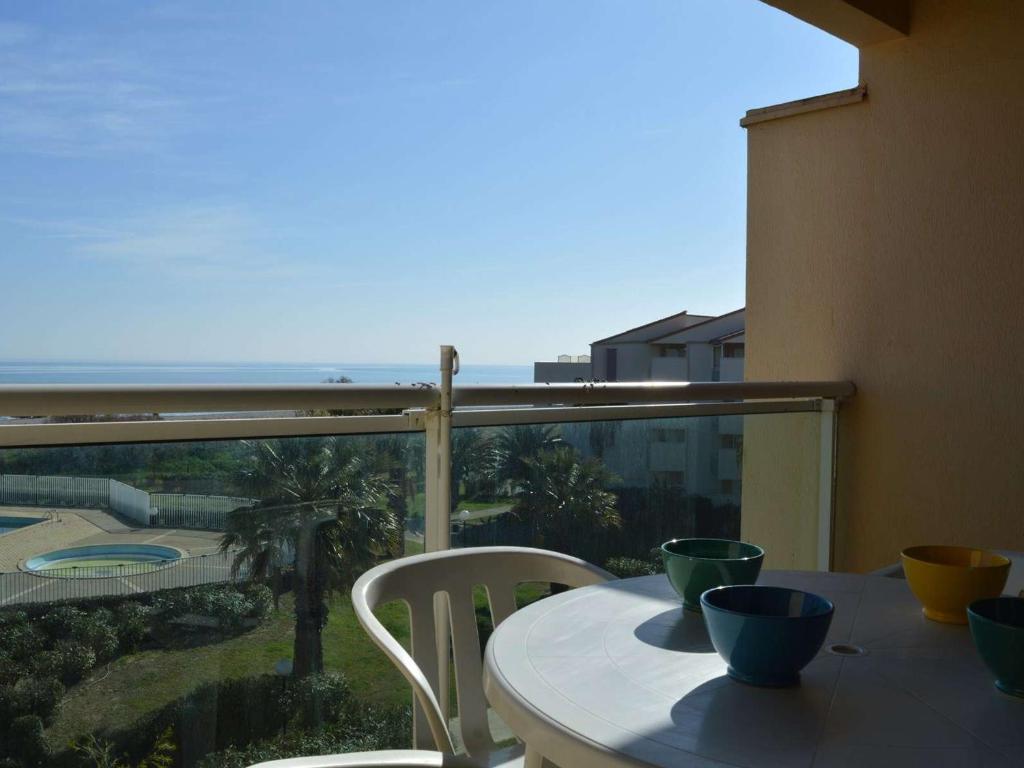 une table et des chaises sur un balcon avec vue sur l'océan dans l'établissement Appartement en Front de Mer avec Piscine et Parking Privé - 2 Chambres pour 6 Personnes, Saint-Cyprien - FR-1-225D-52, à Saint Cyprien Plage