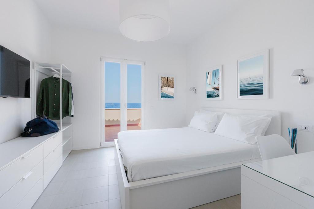 a white bedroom with a bed and a tv at Puolo Seaside Apartment 2 in Massa Lubrense