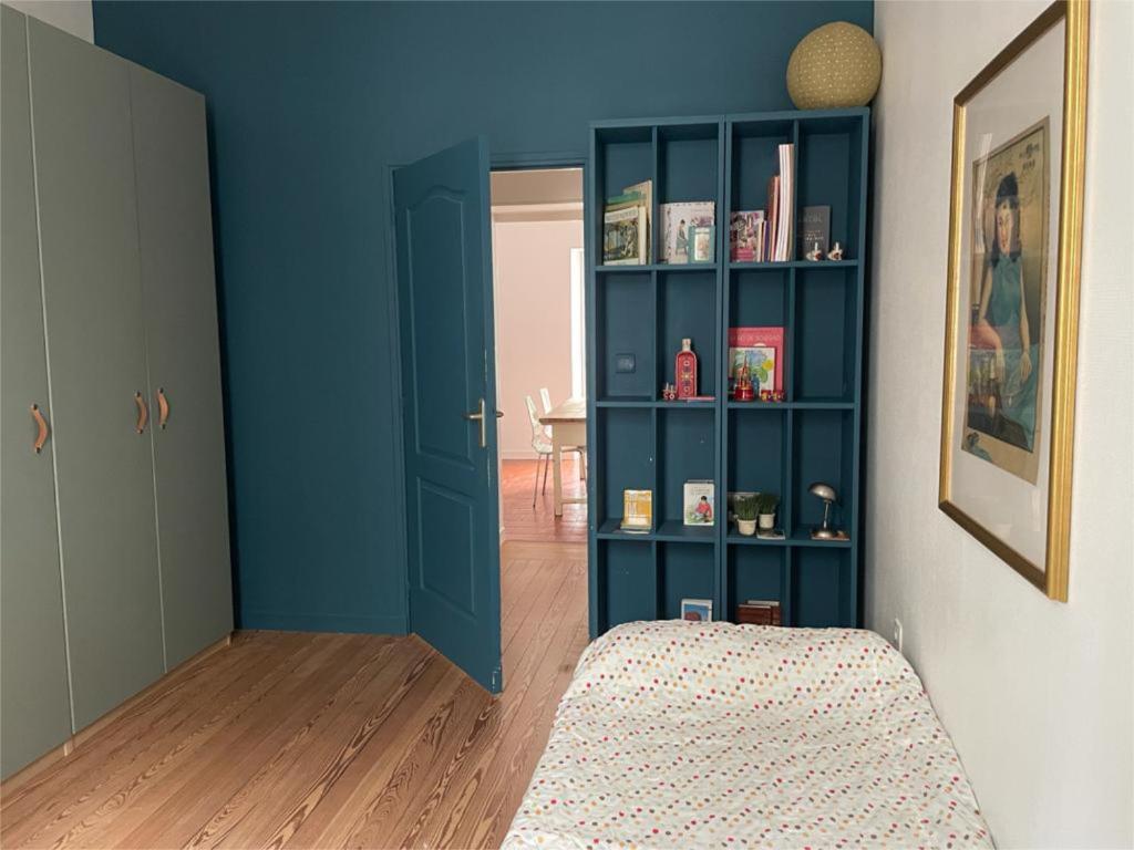 um quarto com uma parede azul e uma estante de livros em Appartement cœur de Ville Vichy em Vichy