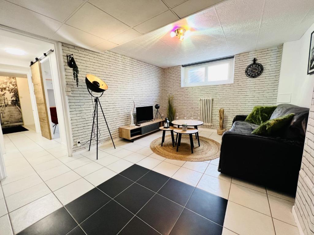 uma sala de estar com um sofá preto e uma mesa em L Autre-Mans - Gare - Atypique - 4 Personnes - Rêve au Mans em Le Mans