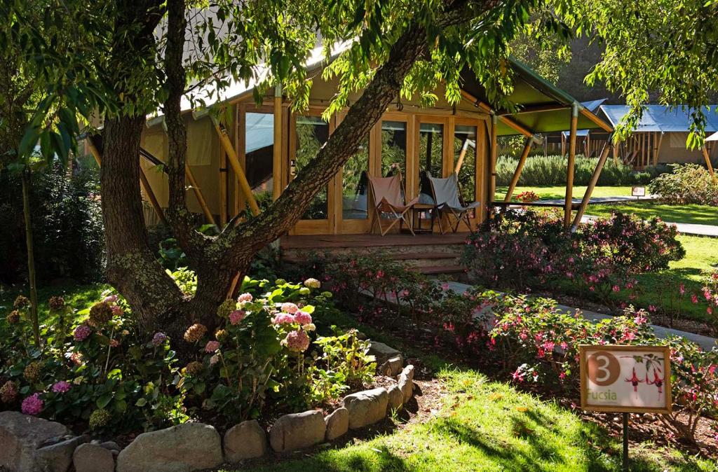 ein Haus mit einem Baum und Blumen im Hof in der Unterkunft Las Qolqas EcoResort Ollantaytambo in Ollantaytambo