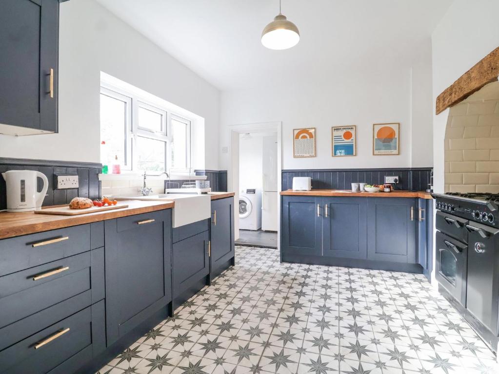 une cuisine avec des armoires bleues et un sol carrelé dans l'établissement Beautiful 4 Bed Beach House - Pool table & Parking, à Pakefield