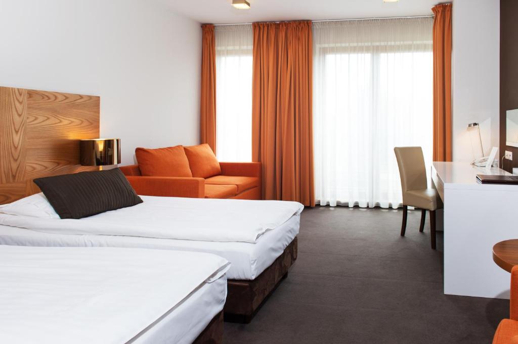a hotel room with two beds and a desk at Bazuny Hotel&Spa in Kościerzyna