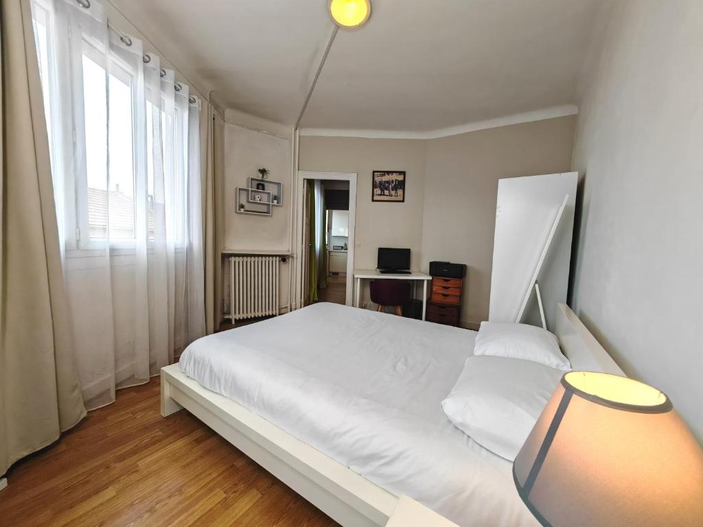 Schlafzimmer mit einem großen weißen Bett und einem Schreibtisch in der Unterkunft Balcon / 2 pièces aux Lilas in Les Lilas