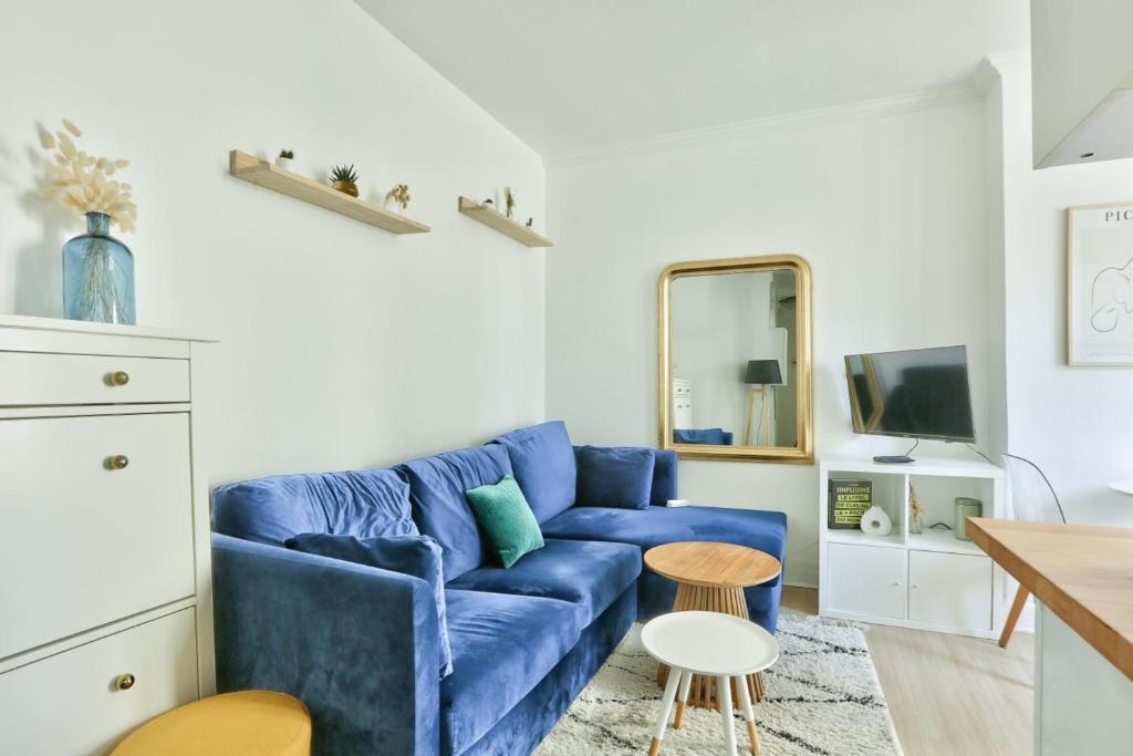 een woonkamer met een blauwe bank en een tafel bij Pretty 24 m near Batignolles in Parijs
