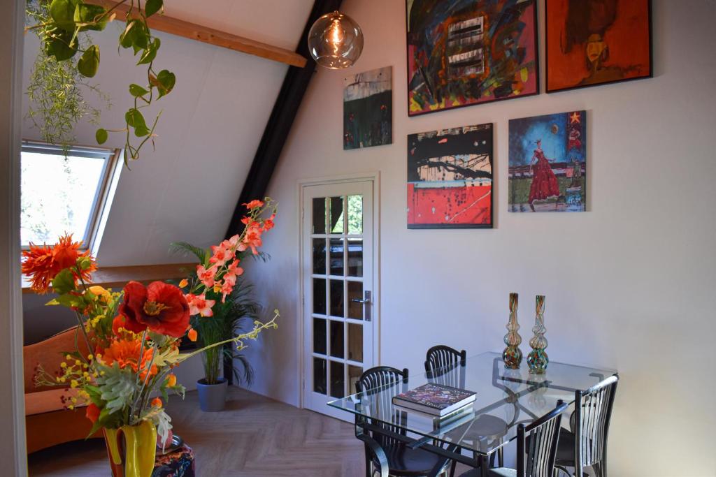 ein Esszimmer mit einem Glastisch und Blumen an der Wand in der Unterkunft Sfeervol appartement 'Le Boulanger' in Franeker. in Franeker