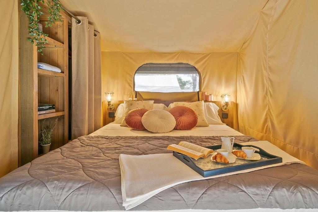 a bed in a tent with a tray of food on it at Càmping Castell Montgrí **** in L'Estartit