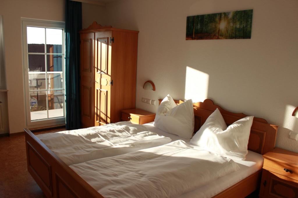 a bedroom with a bed with white sheets and a window at Pension Dorfengel in Berolzheim