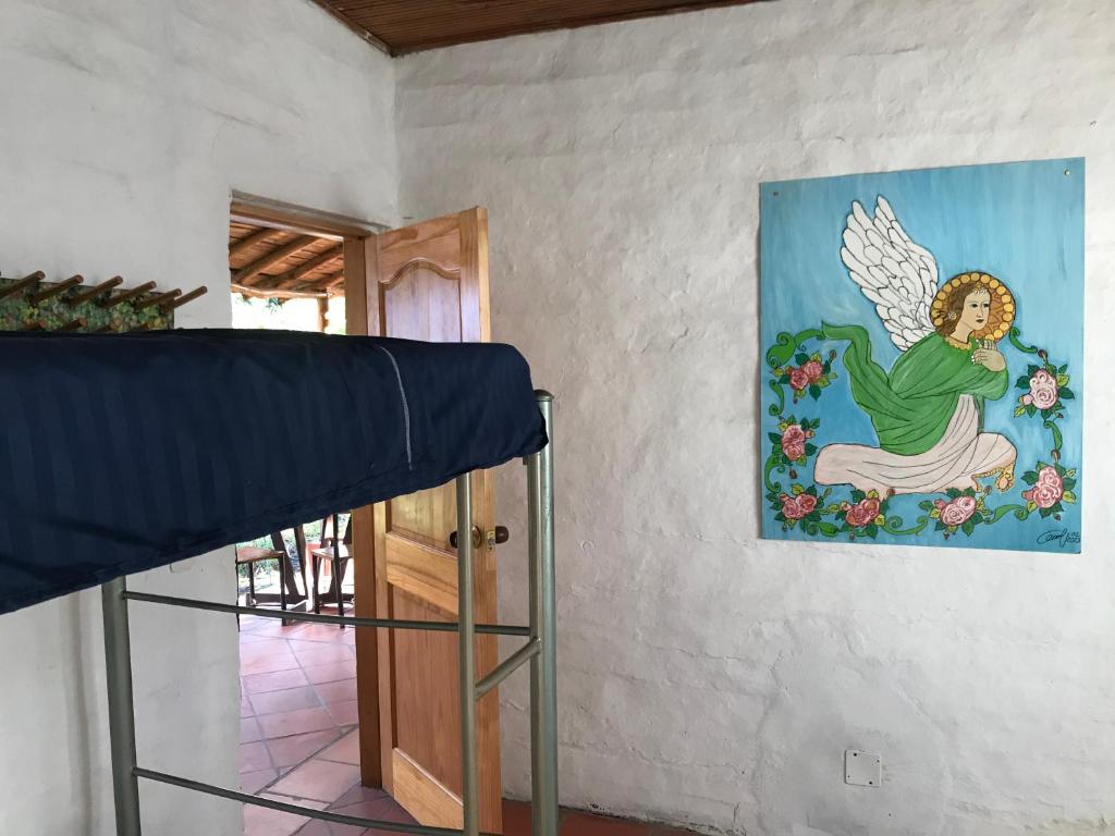 1 dormitorio con una pintura de ángel en la pared en RiverMan Hostel, Tourism and Friends en Jagua