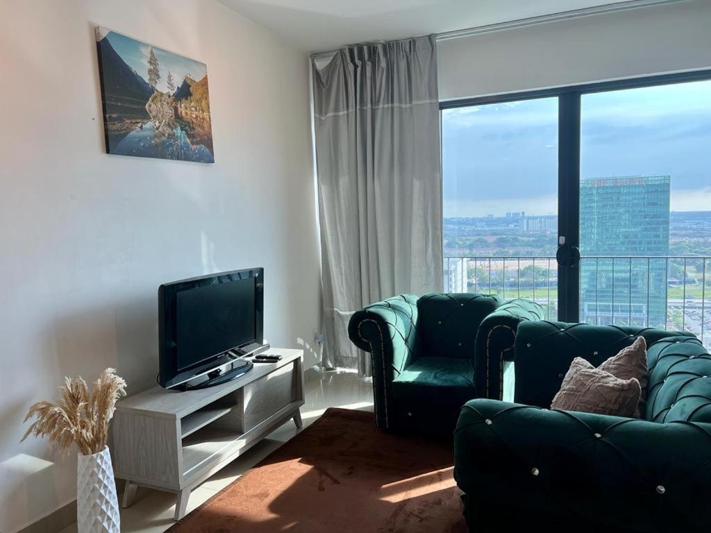 Una sala de estar con un televisor de pantalla plana y un sofá. en Welcome Suite at Trefoil Setia Alam, en Shah Alam