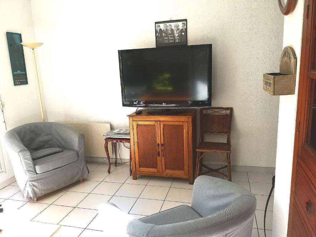 a living room with a flat screen tv and two chairs at 4SAP22 Appartement climatisé avec double terrasses in Collioure