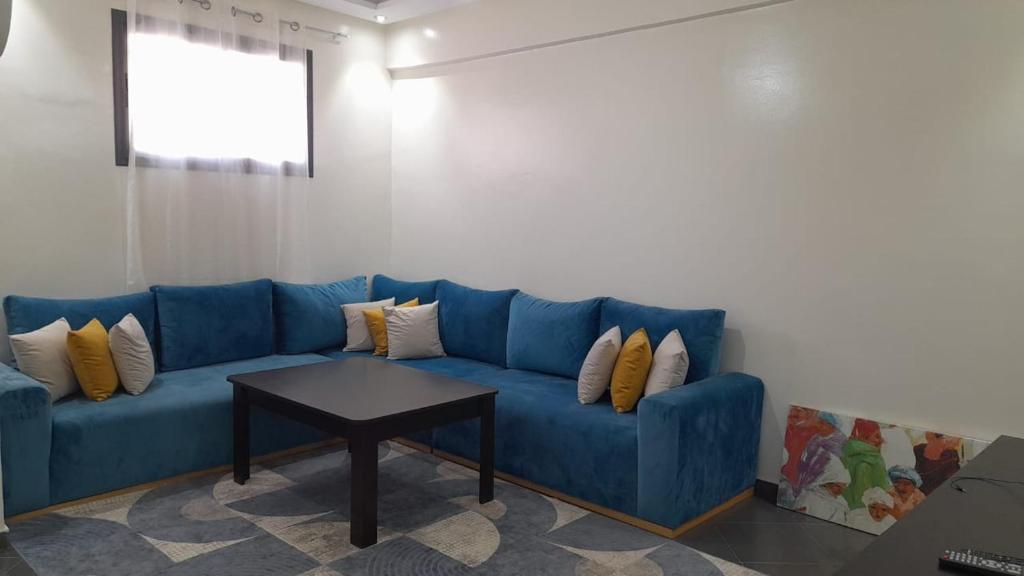 Sofá azul en la sala de estar con mesa en Appartement proche du centre, en Agadir