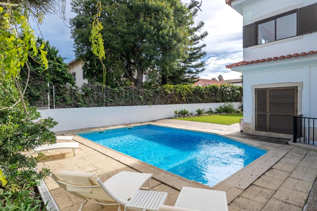 a swimming pool with chairs and a house at Oeiras apt in Spacious Villa - Shared Pool in Oeiras
