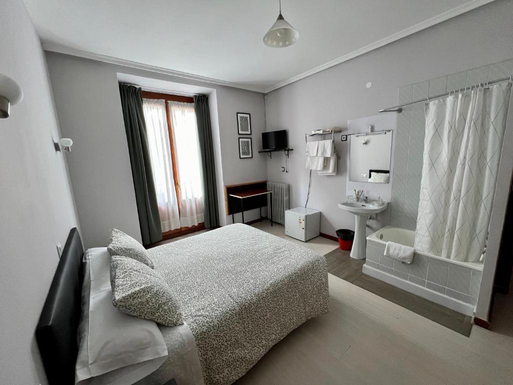 a white bedroom with a bed and a sink at Hostal Conde De Alba in Madrid