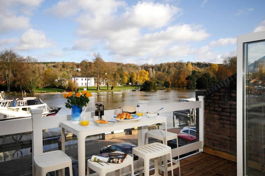 een tafel op een balkon met uitzicht op een rivier bij The Oars - Riverfront Property in Henley on Thames