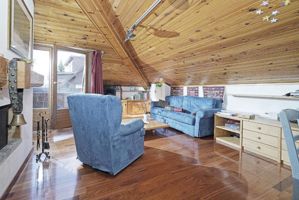 salon z niebieskimi krzesłami i drewnianym sufitem w obiekcie iFlat Madonna di Campiglio Penthouse Brenta w Madonna di Campiglio