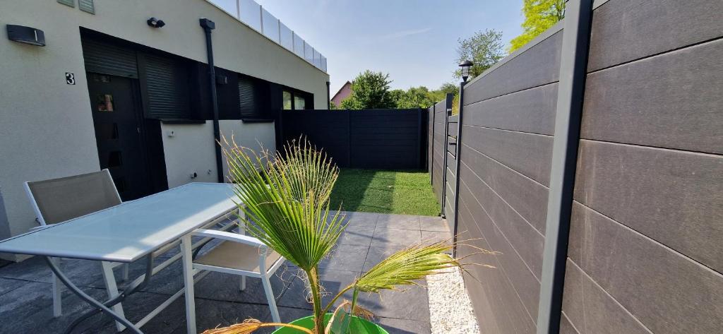 eine kleine Terrasse mit einem Tisch und einem Zaun in der Unterkunft au petit canal de Colmar 3 in Kunheim