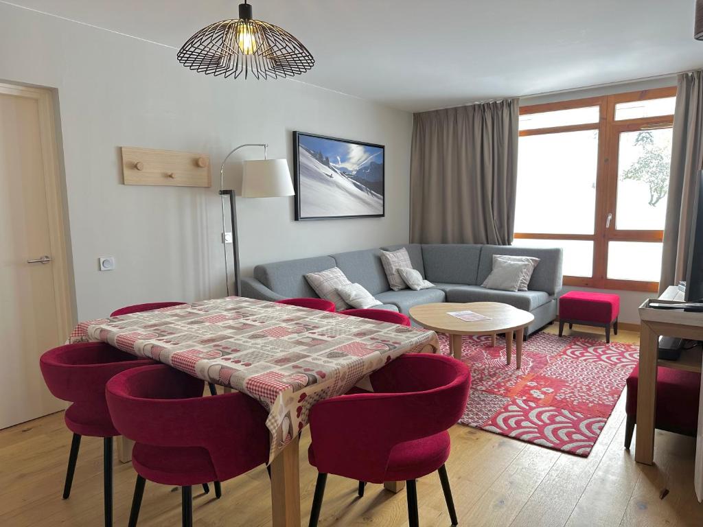 - un salon avec une table et des chaises rouges dans l'établissement Les Arcs 1800 : Appartement ski in/out avec spa, à Bourg-Saint-Maurice