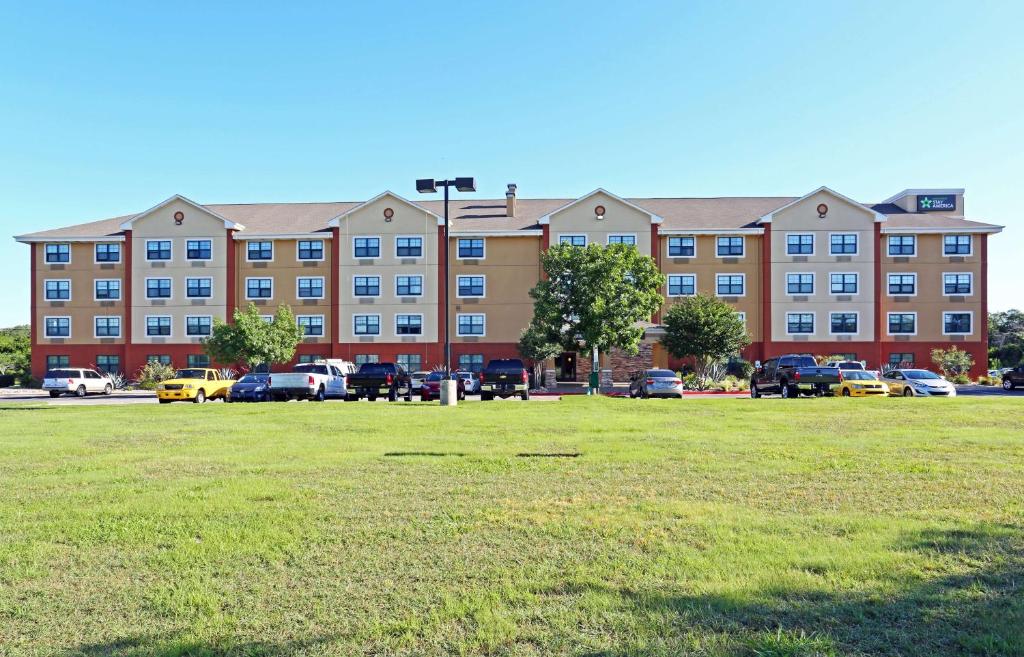 un gran edificio con coches estacionados en un estacionamiento en Extended Stay America Suites - Austin - Southwest en Austin