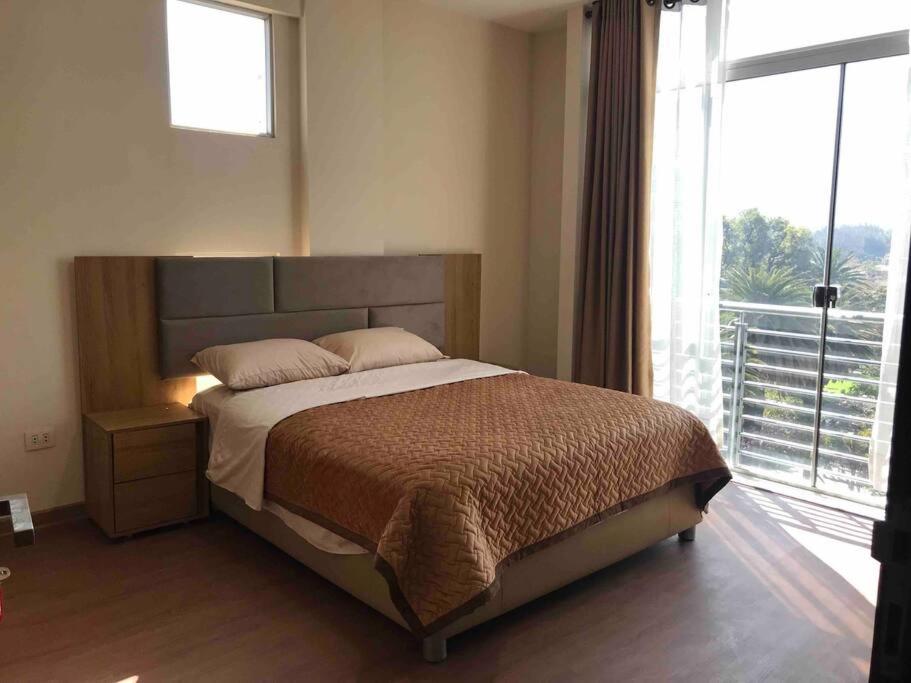 1 dormitorio con cama y ventana grande en Apartamento 1 cómodo, en Cochabamba
