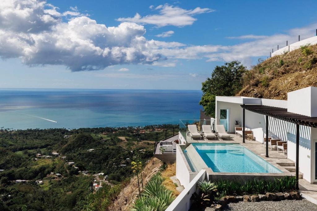 ein Haus mit Pool auf einem Hügel mit Meer in der Unterkunft Adults Only! Ocaso Luxury Villas Entire Property in Rincon