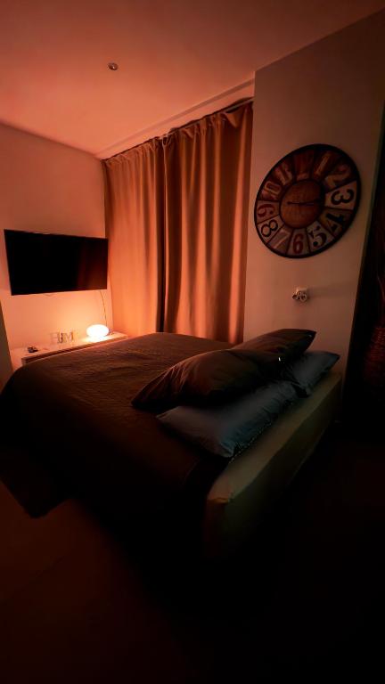 une chambre avec un lit et une horloge au mur dans l'établissement By Nuit-Parisienne : city-view, à Villemomble