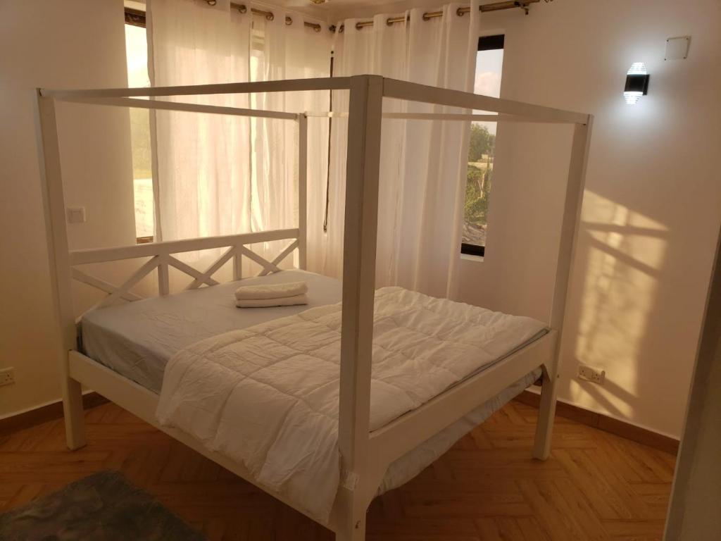 a white bed with a canopy in a room at Casa Marabella A2 in Diani Beach
